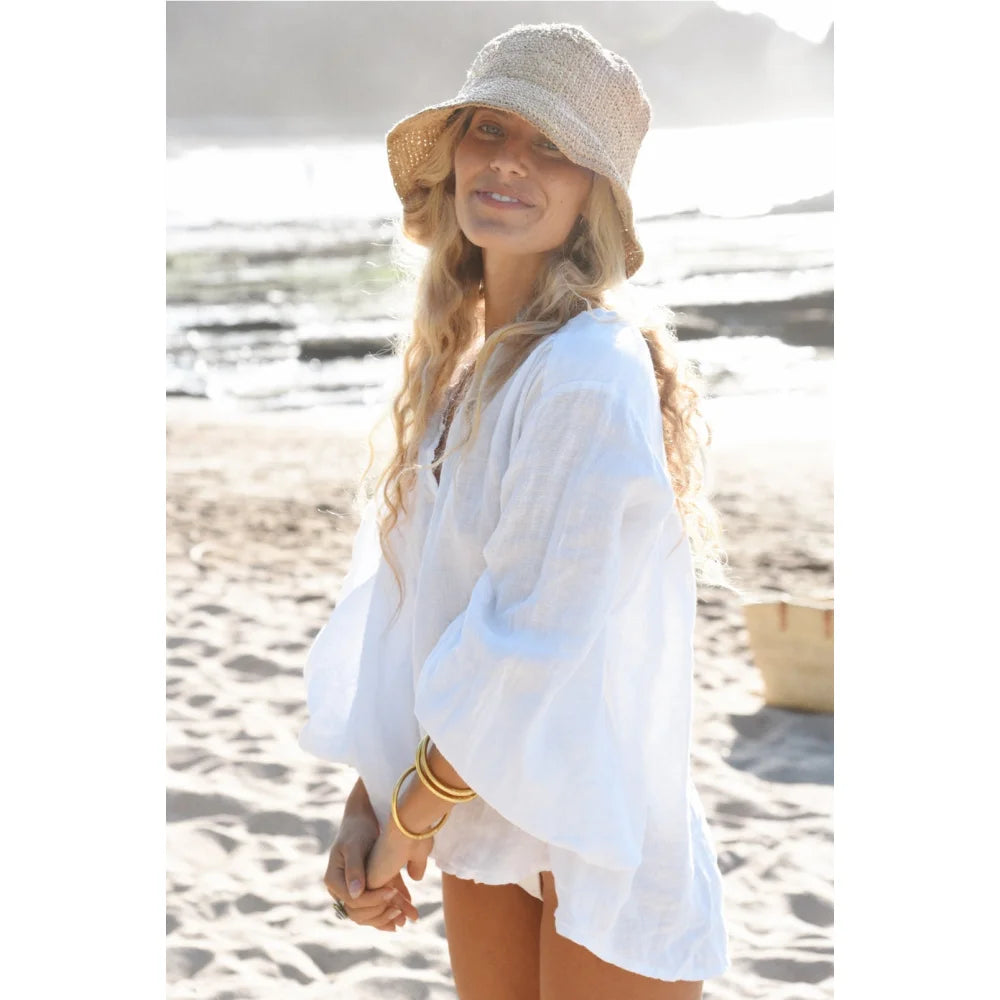 Frau in weißer Leinenbluse und Strohhut am Strand für Bluse Lily Blanco
