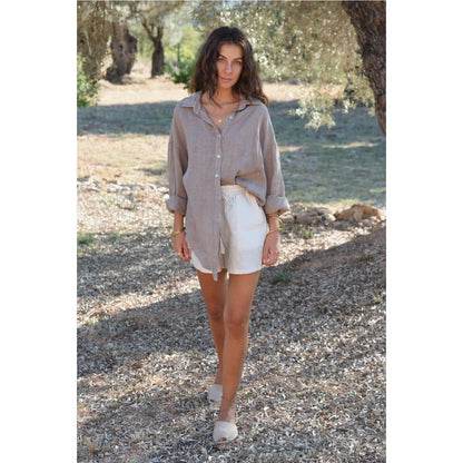 Frau trägt lockere beigen Leinenbluse und weiße Leinenshorts im Produkt Bluse Palma Taupe