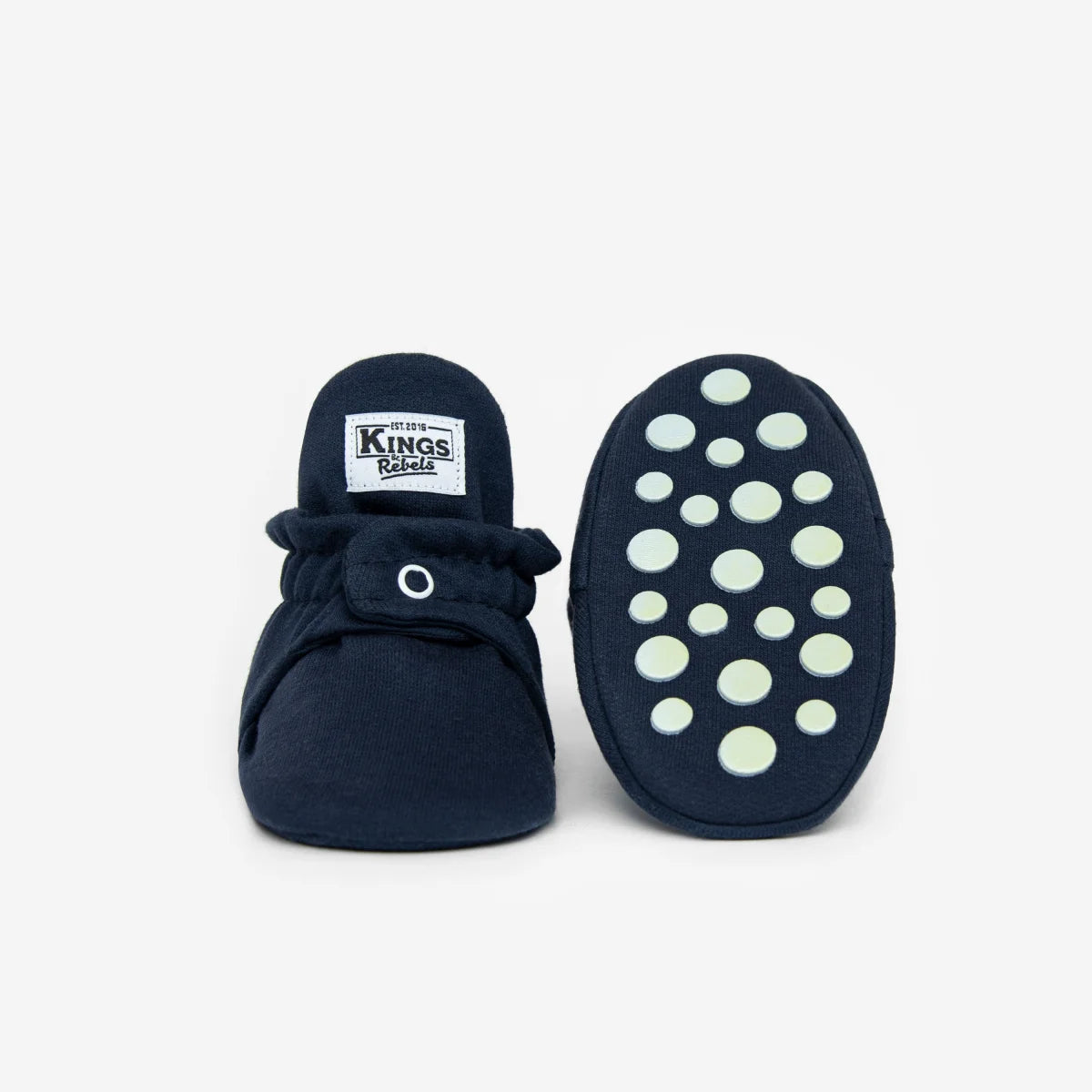 Navy blaue baby booties aus weicher baumwolle mit weißem knopf und grünen rutschfesten punkten für nachhaltige babykleidung schweiz