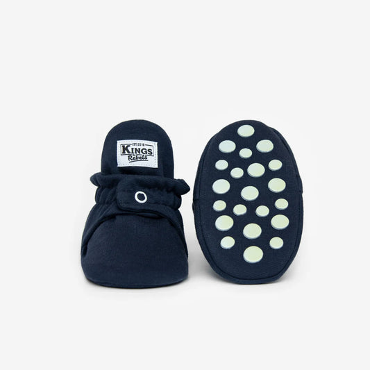 Navy blaue baby booties aus weicher baumwolle mit weißem knopf und grünen rutschfesten punkten für nachhaltige babykleidung schweiz