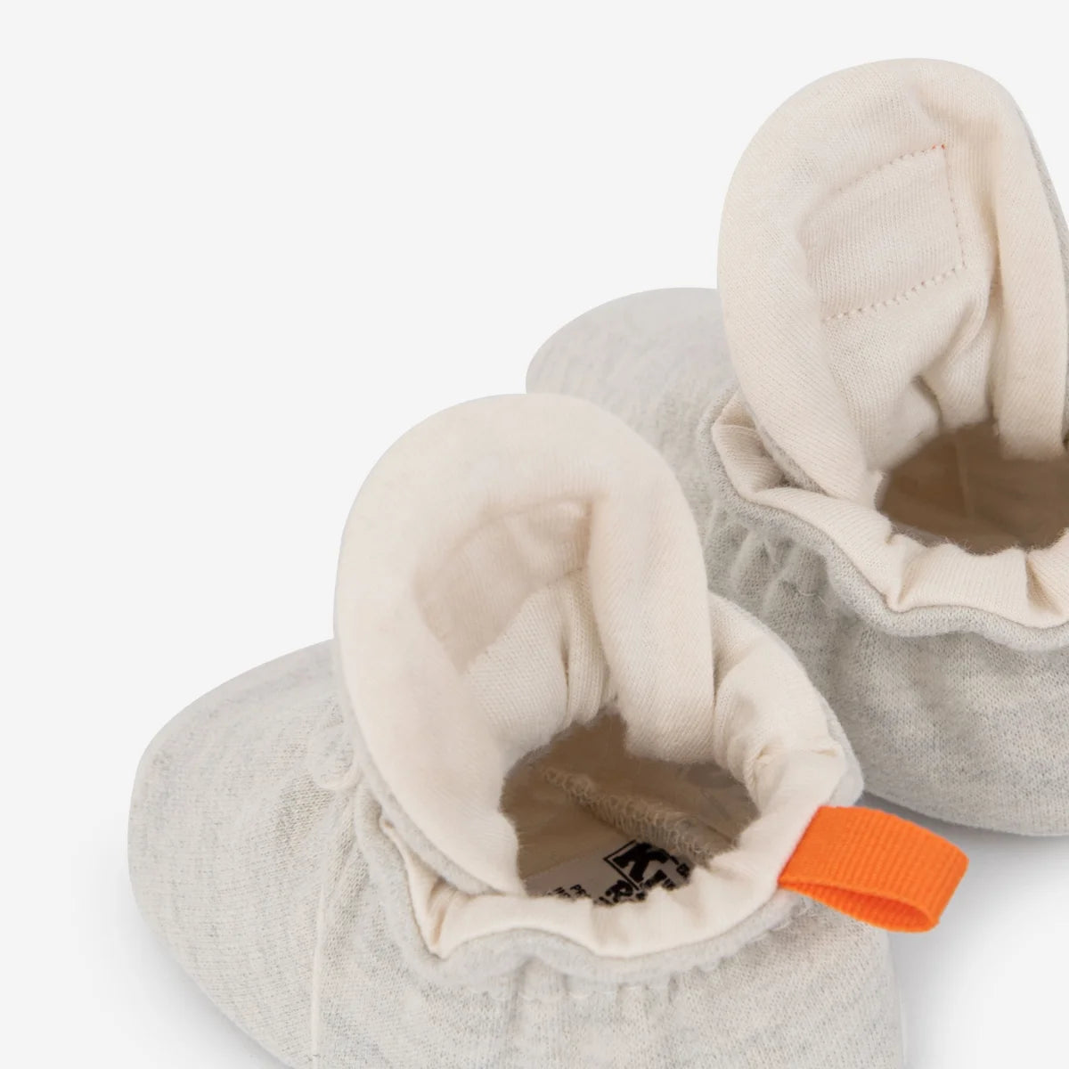 Weiche grau gestrickte babybooties mit cremefarbener plüschfütterung und oranger ziehschlaufe nachhaltige babykleidung schweiz