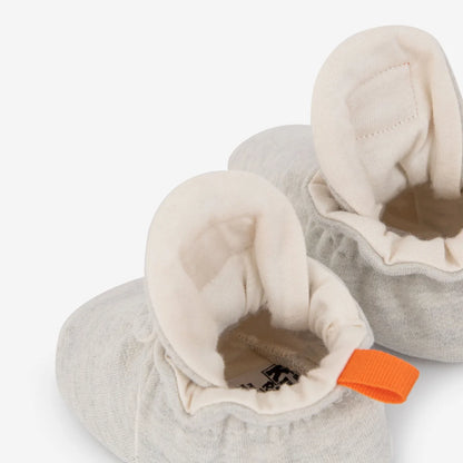 Weiche grau gestrickte babybooties mit cremefarbener plüschfütterung und oranger ziehschlaufe nachhaltige babykleidung schweiz
