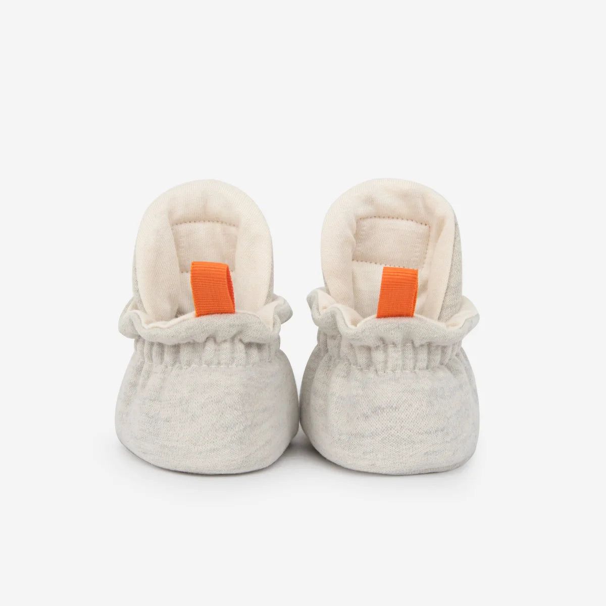 Weiche offwhite cotton gripper baby booties mit gerüschtem bund und orangefarbenen ziehhilfen für nachhaltige babykleidung schweiz