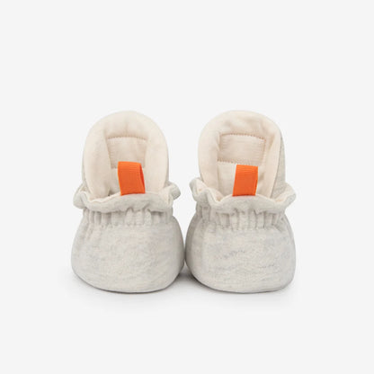 Weiche offwhite cotton gripper baby booties mit gerüschtem bund und orangefarbenen ziehhilfen für nachhaltige babykleidung schweiz