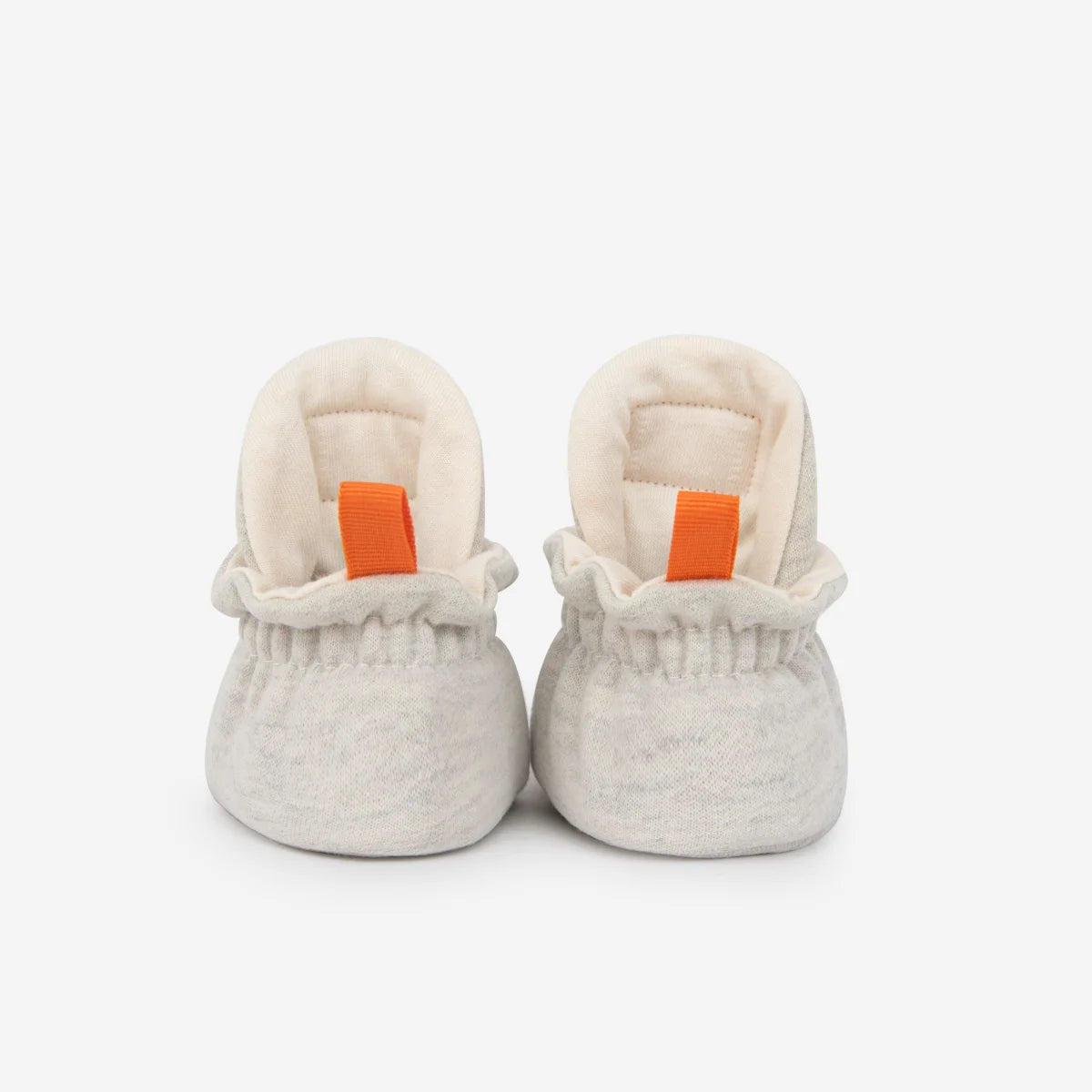 Weiche off-white babybooties aus baumwolle mit orangefarbenen ziehschlaufen für neugeborene geschenke nachhaltige babykleidung schweiz