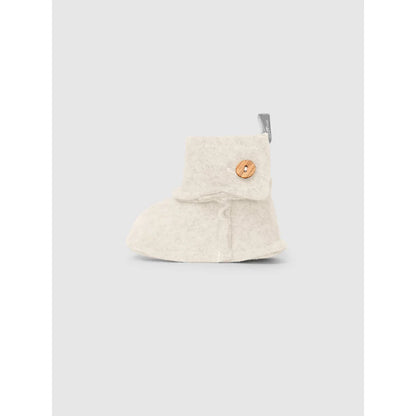 Ein cremefarbener Babybootie mit Holzknopf aus Fleece im Produkt Booties in Fleece Sand