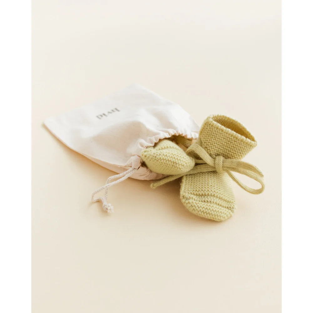 Paar blassgrüne, gestrickte Babybooties mit Zugbeutel als Produkt Booties | hellgelb