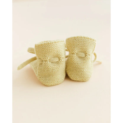 Paar zartgelber gestrickter Babystiefel mit Schleifenbindungen in Produkt Booties