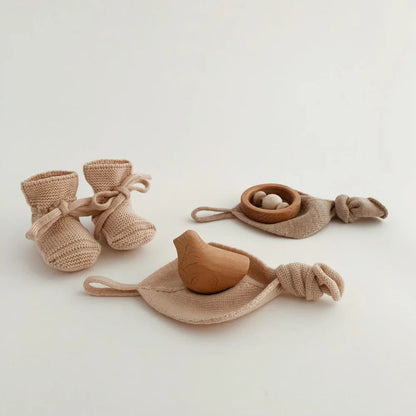 Set aus gestrickten Baby-Booties und Holzspielzeugvögeln in Stoffnestern