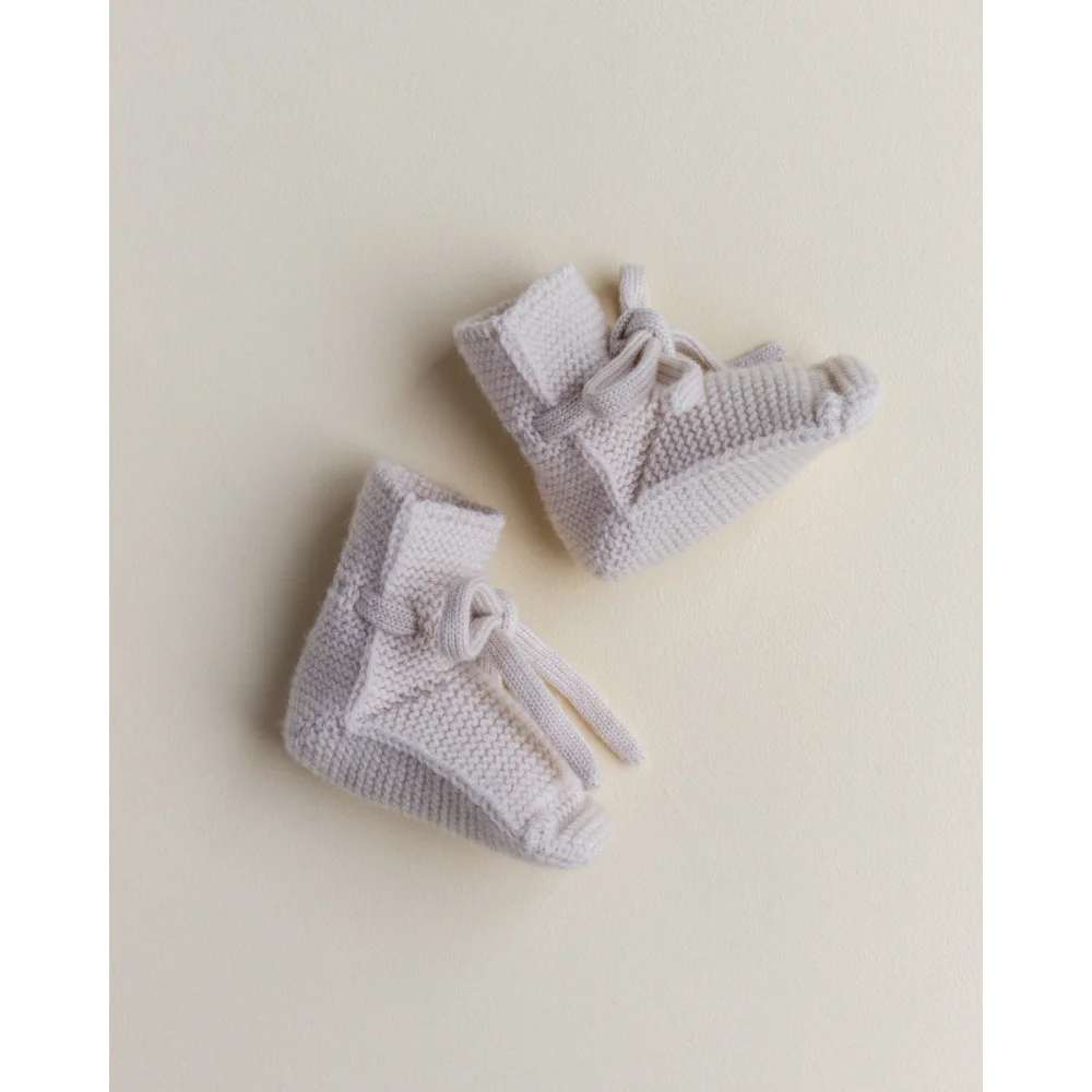 Paar gestrickte Babybooties in hellem Grau und Off-White für stilvolle Kleinkinder