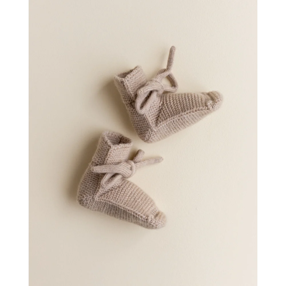 Paar gestrickte Babybooties mit Schleifen in Sandfarbe