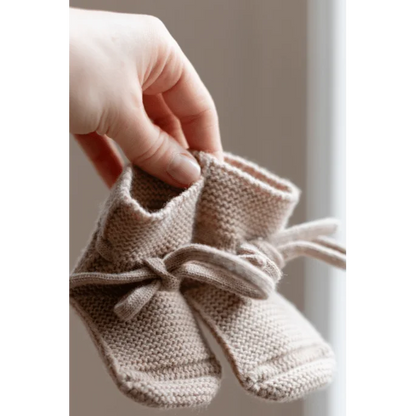 Ein Paar gestrickte Babybooties mit Bindeschnürung in der Farbe Sand