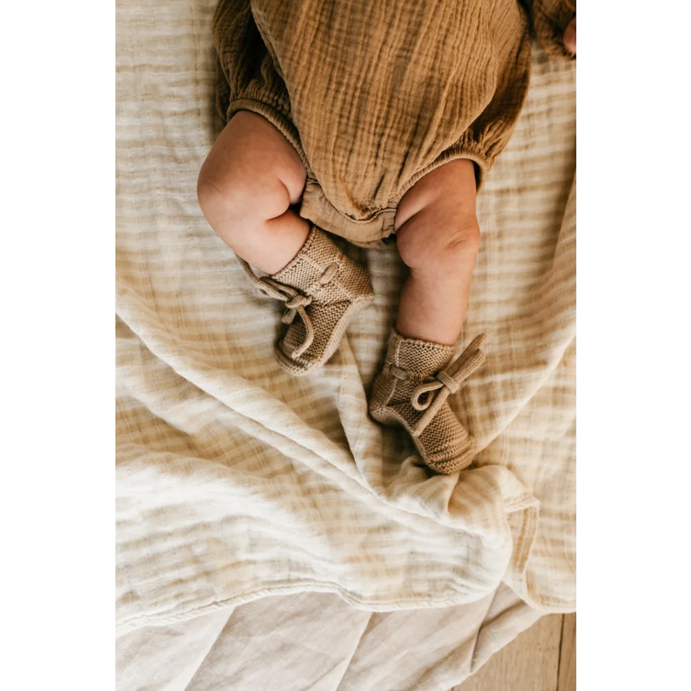 Babylegs in gestrickten Sandbooties auf weichem Stoffuntergrund