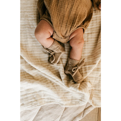 Babylegs in gestrickten Sandbooties auf weichem Stoffuntergrund