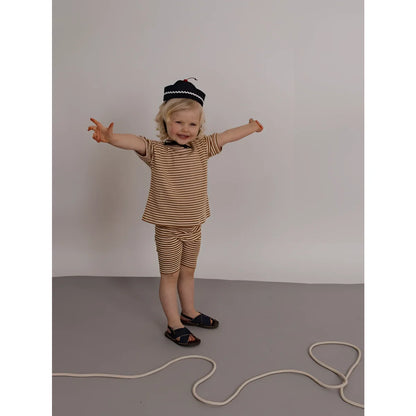 Kleinkind in Boxy T-Shirt Copper Stripes, beige-braun gestreift, mit Shorts, Sandalen und Baskenmütze