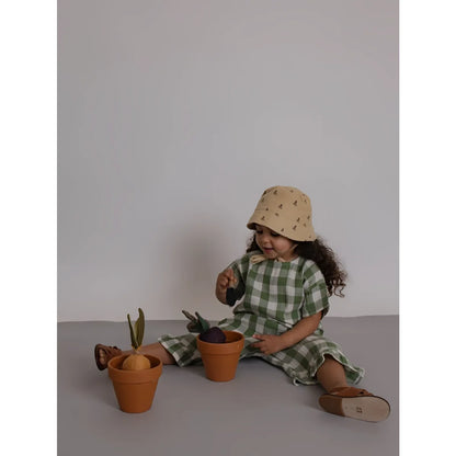 Kleinkind in Dill-Gingham Boxy T-Shirt sitzt mit Töpfen auf Boden