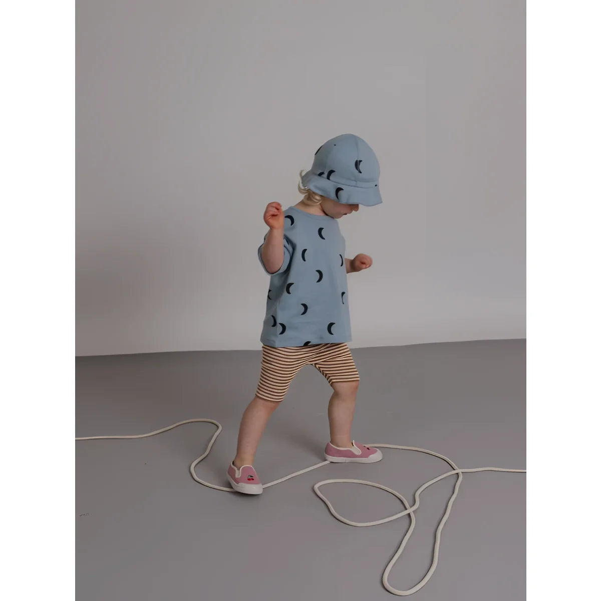 Kind Boxy T-Shirt River Midnight: Kind in hellblauem Bucket-Hut und Top mit Mondmotiven