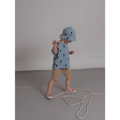 Kind Boxy T-Shirt River Midnight: Kind in hellblauem Bucket-Hut und Top mit Mondmotiven