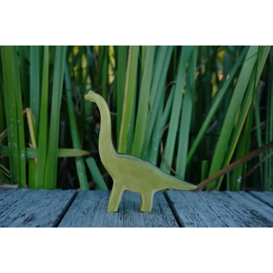 Hellgrüner Brachiosaurus Holzfigur mit langem Hals auf grauer Oberfläche