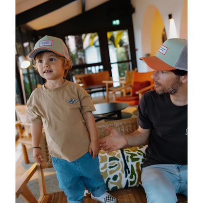 Beige trucker cap anis mit mesh-rückseite, orangefarbener schirm und kleinem rechteckigem patch vorne