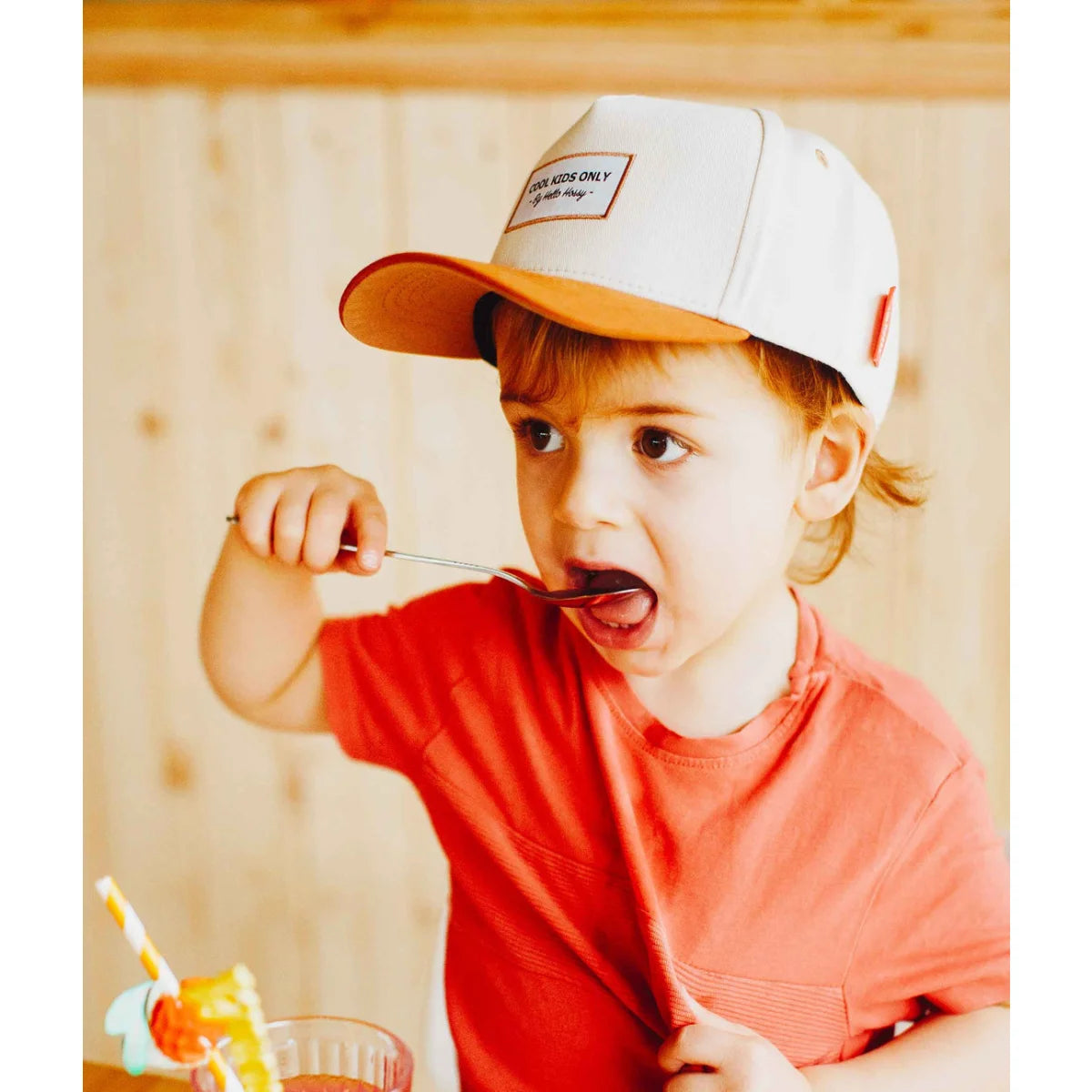 Ein kind trägt eine beige cap mini mit einem weißen und orangen schirm und einem rechteckigen patch cool kids only