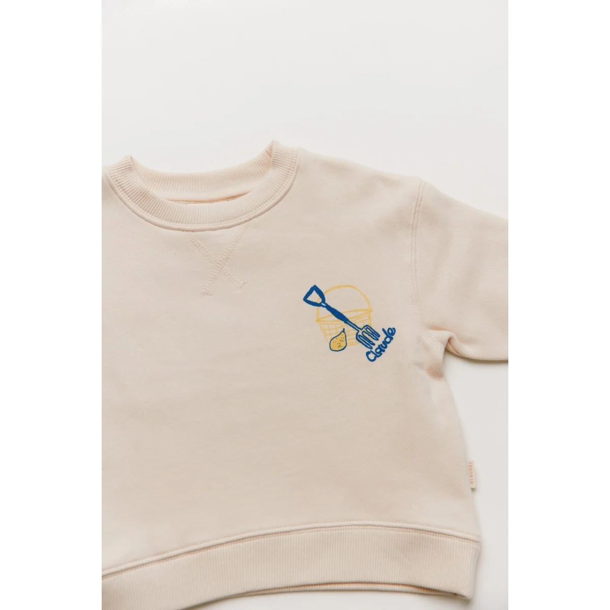 Beiger kindersweatshirt carner grow slowly mit blau gelbem besticktem schaufelmotiv auf der brust