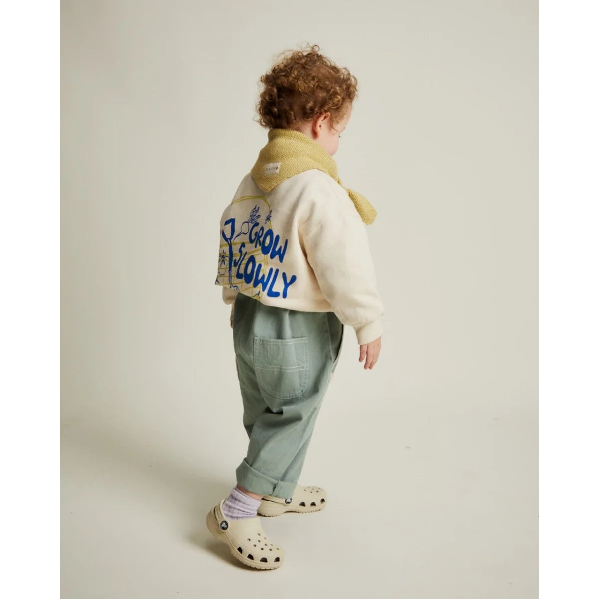 Creamfarbenes bomberjacke mit gelbem shearlingkragen und blauem grow slowly lettering auf der rückseite von carner