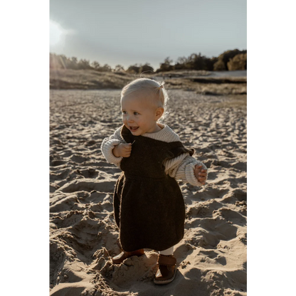 Lächelndes Baby in dunklem Outfit auf einem Sandstrand, Chunky Knit Sweater Oat