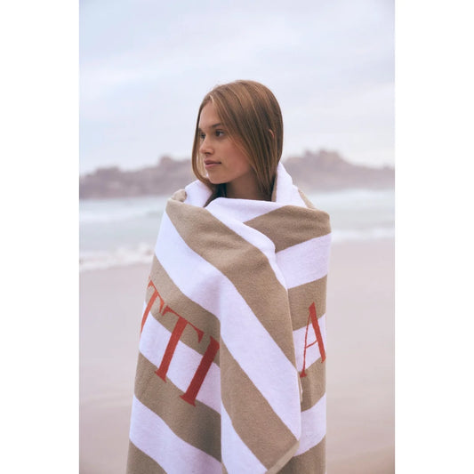 Beige und weiss gestreiftes ciaobadetuch mit roten buchstaben ideal für ökologische baby- und kinderprodukte am strand