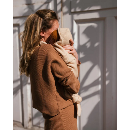 Frau hält Baby in der Sonne mit Cocoon Babydecke in Oat