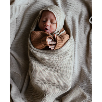 Neugeborenes Baby in einer gestrickten Decke mit einer Schleife um die Brust