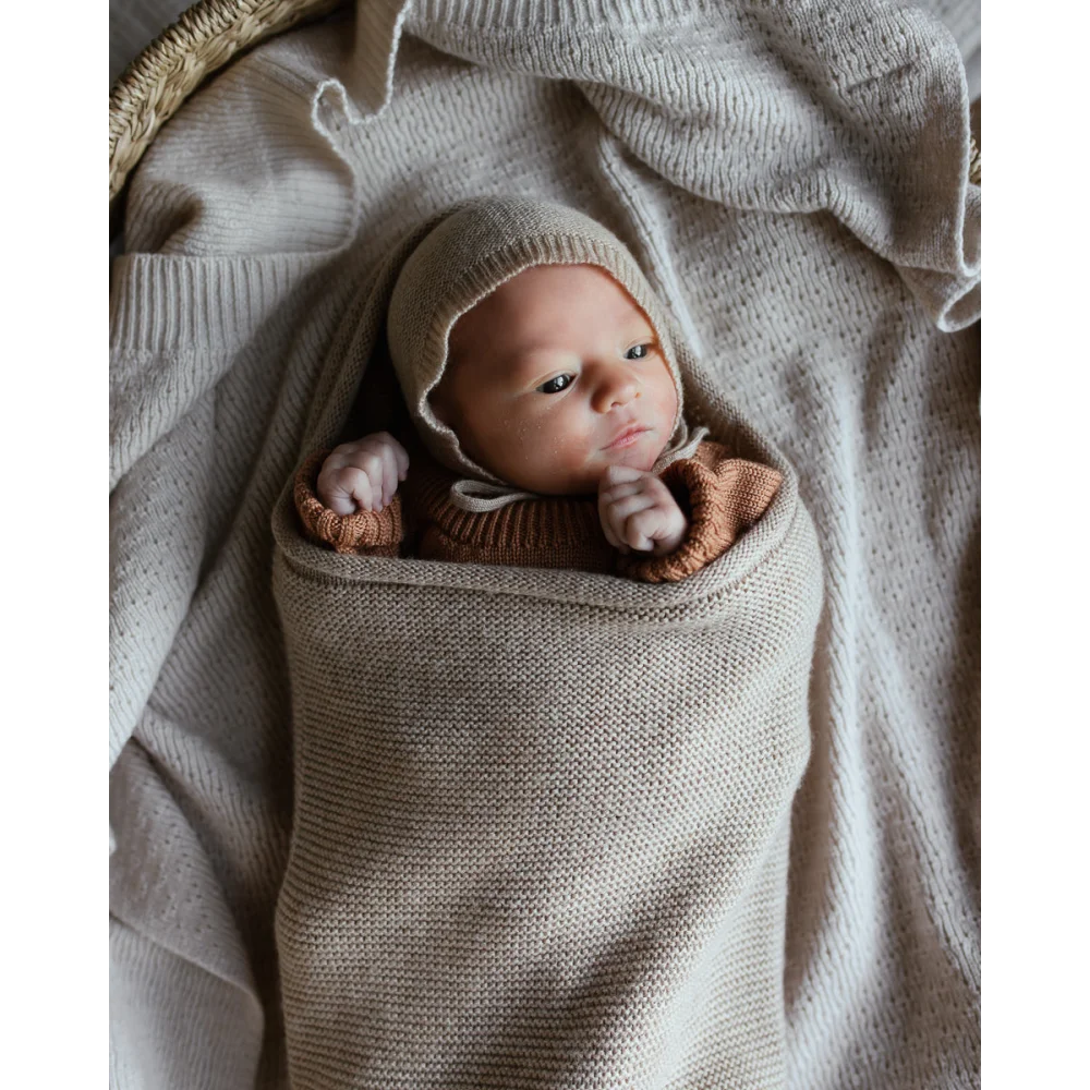 Neugeborenes Baby in einer gestrickten beigen Decke der Cocoon Babydecke | Sand