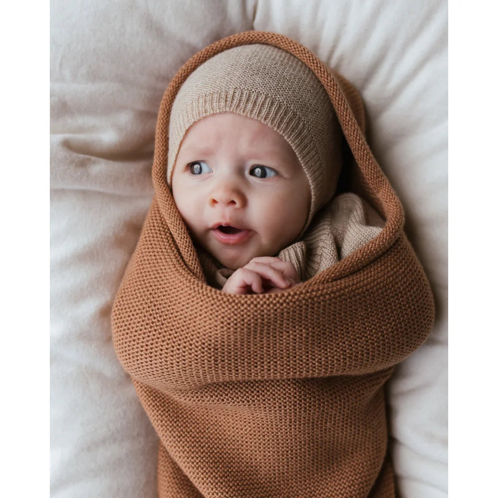 Baby in einer braunen Cocoon Babydecke, Teil der ökologischen Kinderbekleidung