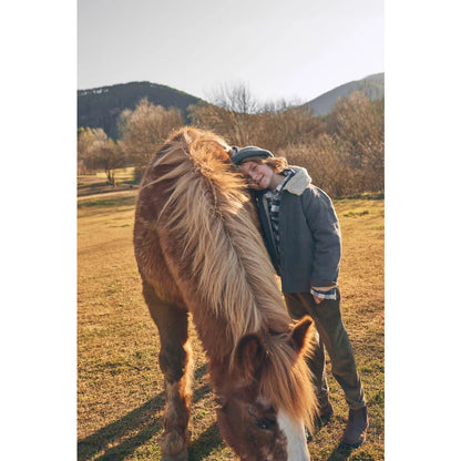 Junge lehnt an einem Pferd, trägt Corduroy-Hosen in Kaki für stilvolle Freizeitmode