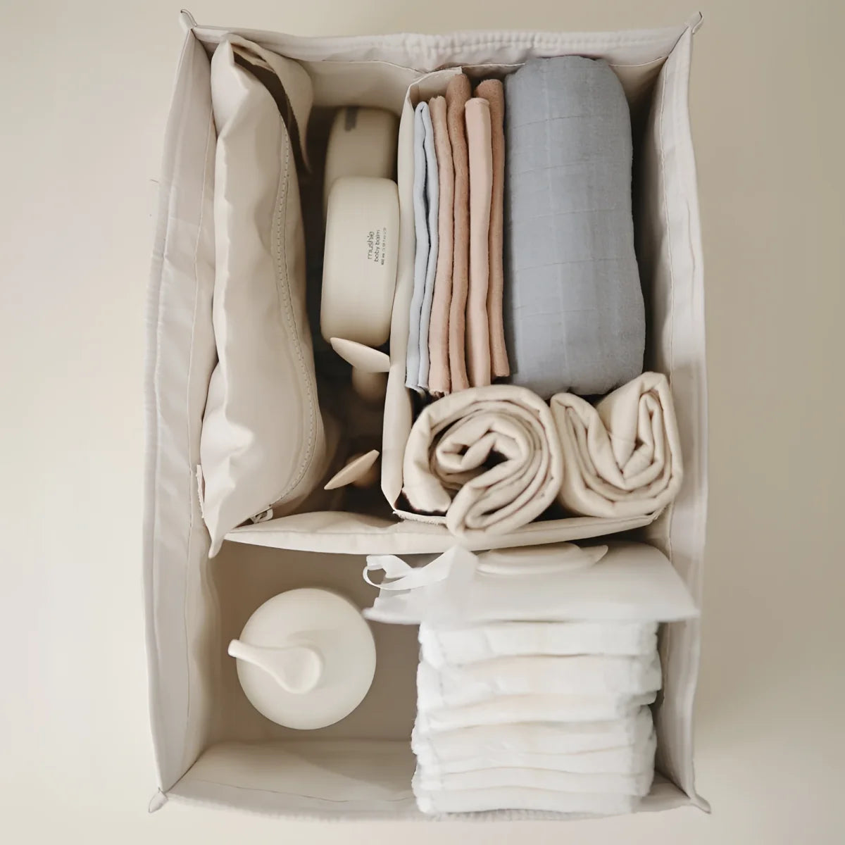 Beige stoff organizer mit ordentlich gefalteter wäsche und babyartikeln im ivory windel caddy
