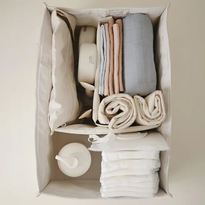 Beige stoff organizer mit ordentlich gefalteter wäsche und babyartikeln im ivory windel caddy