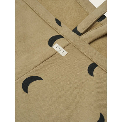 Tan Stoff mit schwarzen Halbmondmustern und kleinem weißen Label für Dungarees Latzhose Dusky Midnight