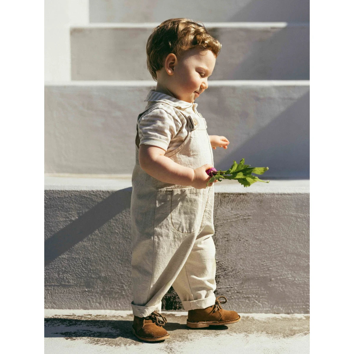 Kind mit umklappbaren Beinabschlüssen in natürlichen Dungarees