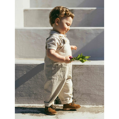 Kind mit umklappbaren Beinabschlüssen in natürlichen Dungarees