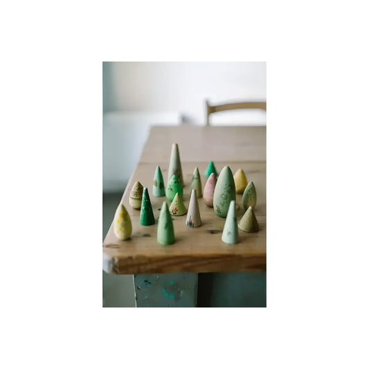 Eine sammlung handbemalter holzbaumfiguren forest tree in sanften grün, gelb und rosa farbtönen