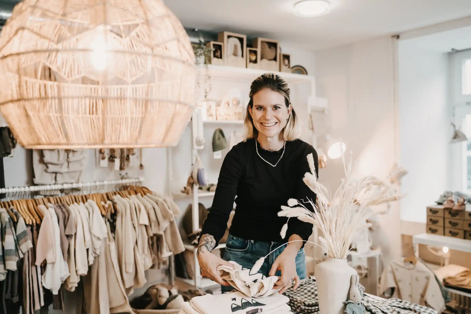Lächelnde Frau hält Stoff in einer Boutique.