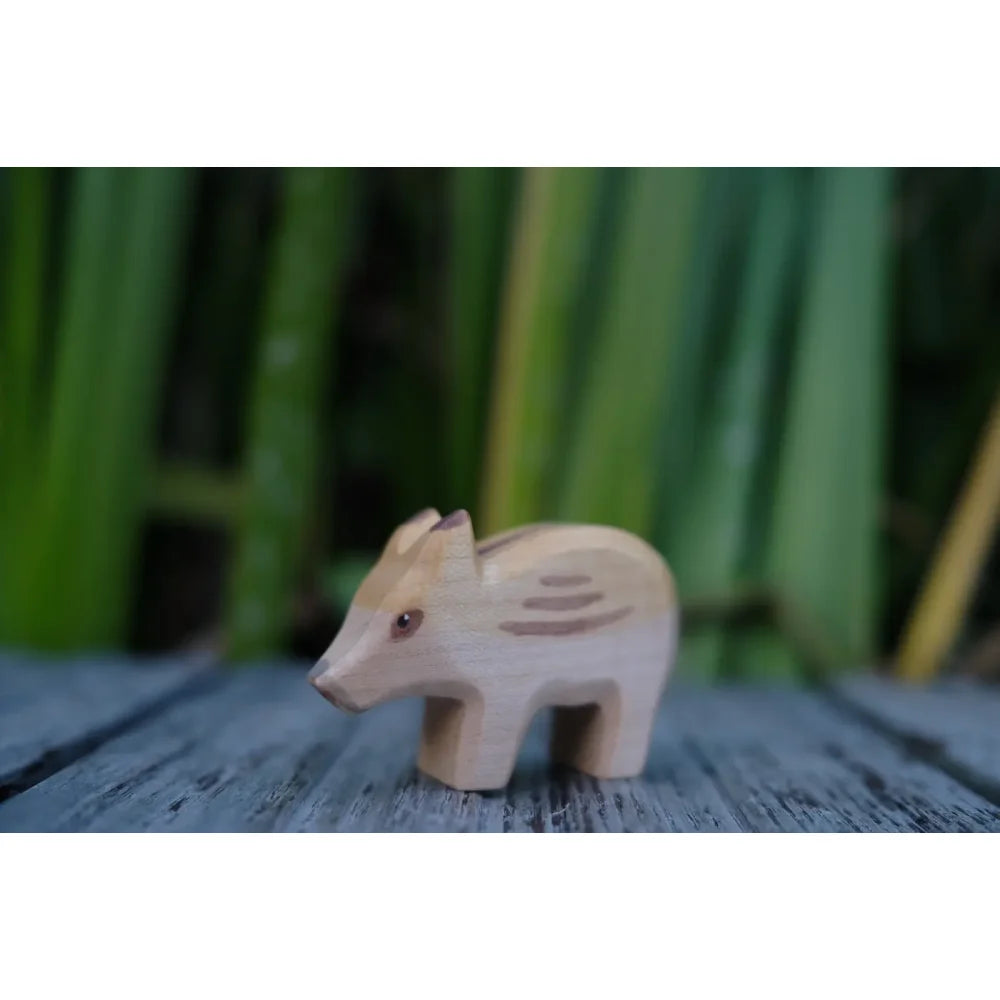Helle Holzfigur eines Baby-Wildschweins mit braunen Streifen, namens Frischling