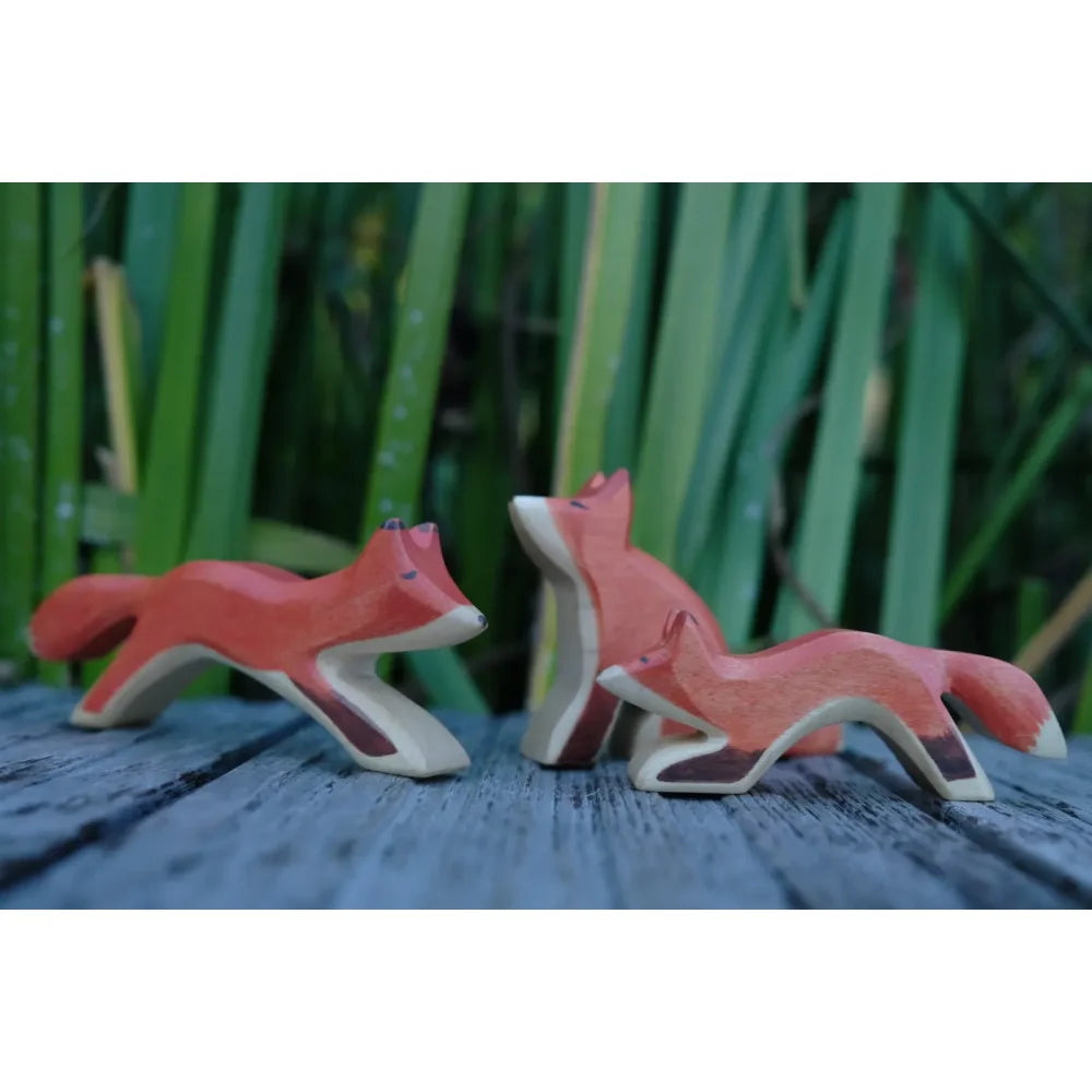 Drei handbemalte Holzfuchsfiguren in Orange mit weißen und braunen Akzenten