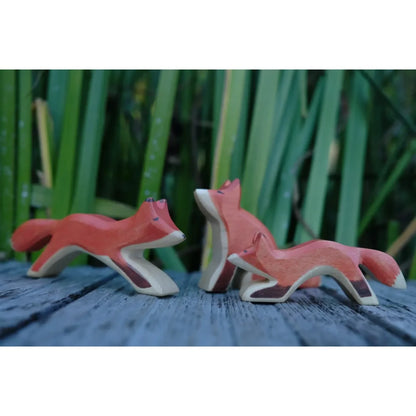 Drei handbemalte Holzfuchsfiguren in Orange mit weißen und braunen Akzenten