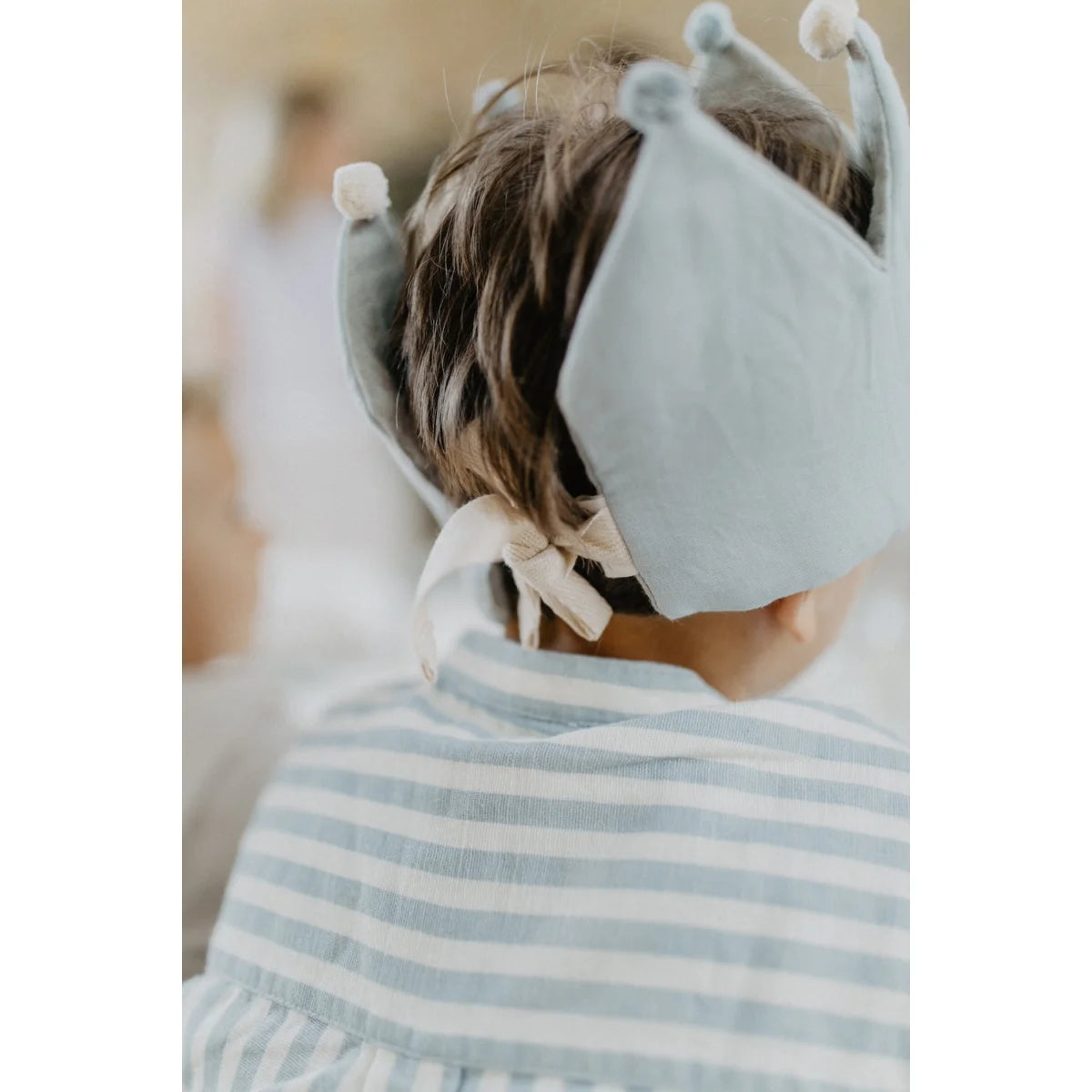 Lichtblaue geburtstagskrone aus plüsch mit weichen bommelspitzen und gebundener schleife für ökologische babyprodukte