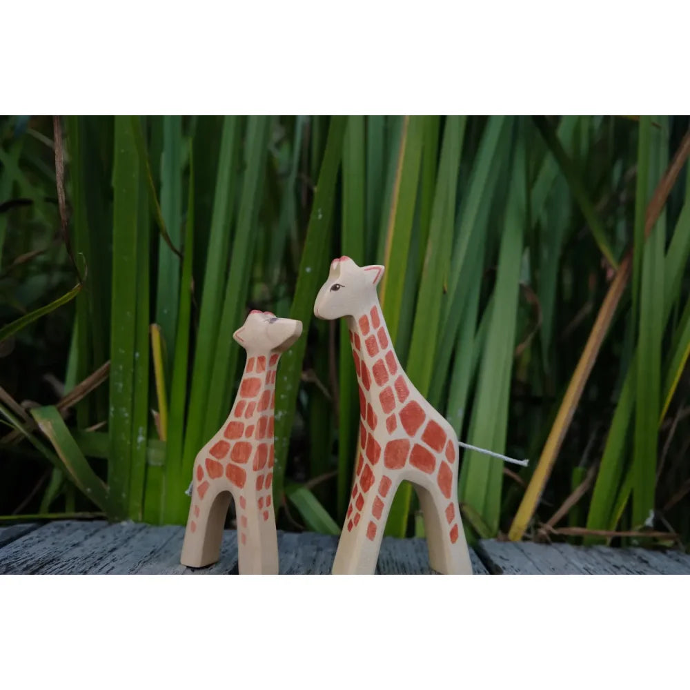 Zwei Holzspielzeug-Giraffen mit hellbraunen Körpern und orange-roten Flecken