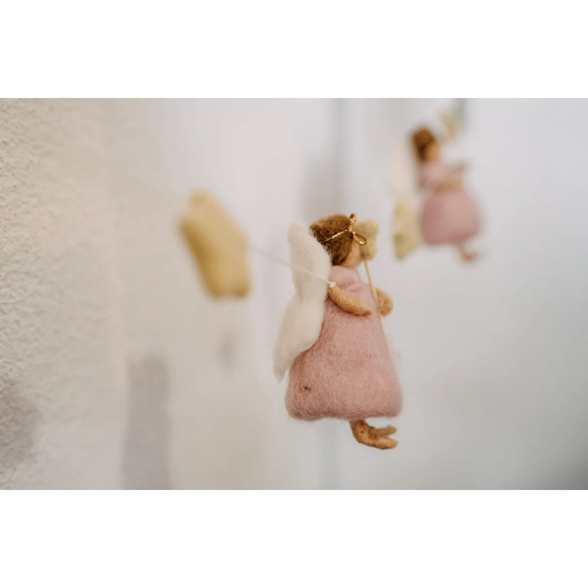 Eine zarte rosa filzfee mit weißen flügeln und goldenem stirnband als ornament für girlande feen und sterne
