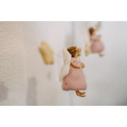 Eine zarte rosa filzfee mit weißen flügeln und goldenem stirnband als ornament für girlande feen und sterne