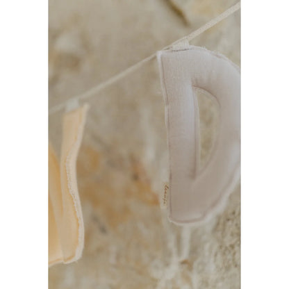 Ein weicher, offwhite stoffbuchstabe d, der an einer schnur in der girlande happy birthday lavender hängt für ökologische baby- & kinderprodukte