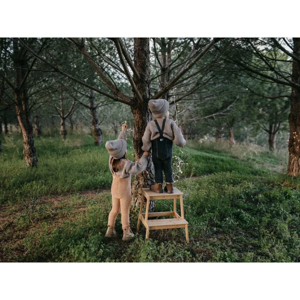 Zwei Kinder auf einer Holztrittleiter im Obstgarten mit Granny Teddy Strumpfhose